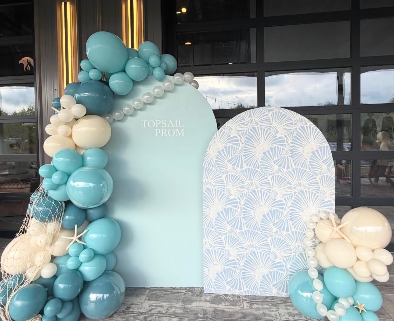 Coastal-themed prom balloon arches in soft blue with seashells