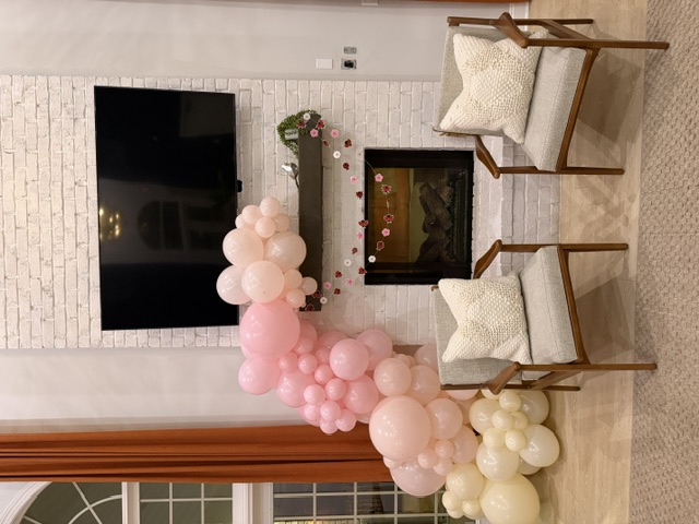 Blush pink balloon garland around a fireplace for Valentine's Day